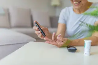 Senior using a glucose meter to get her blood sugar level