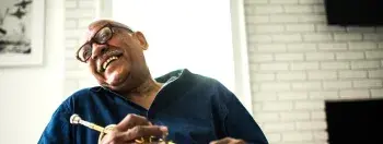 an older man laughing and holding a trumpet