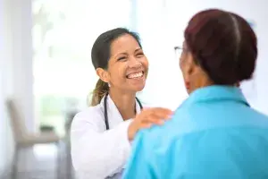 A smiling doctor with her hand on a patient’s shoulder