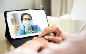 An older woman having a virtual appointment with her doctor using her cell phone