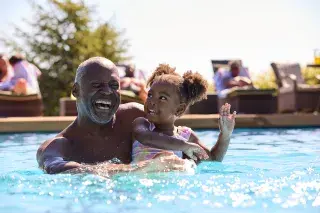 Senior playing with their grandchild in a local swimming pool