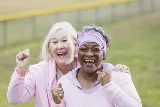 Two senior ladies cheering together while wearing pink for breast cancer awareness