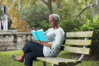 Senior reading a book on a park bench