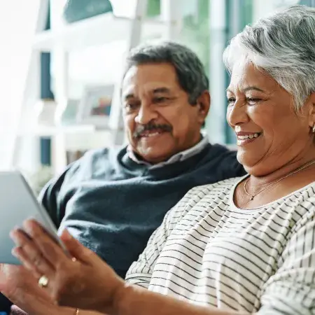 A couple on their couch looking at a tablet together