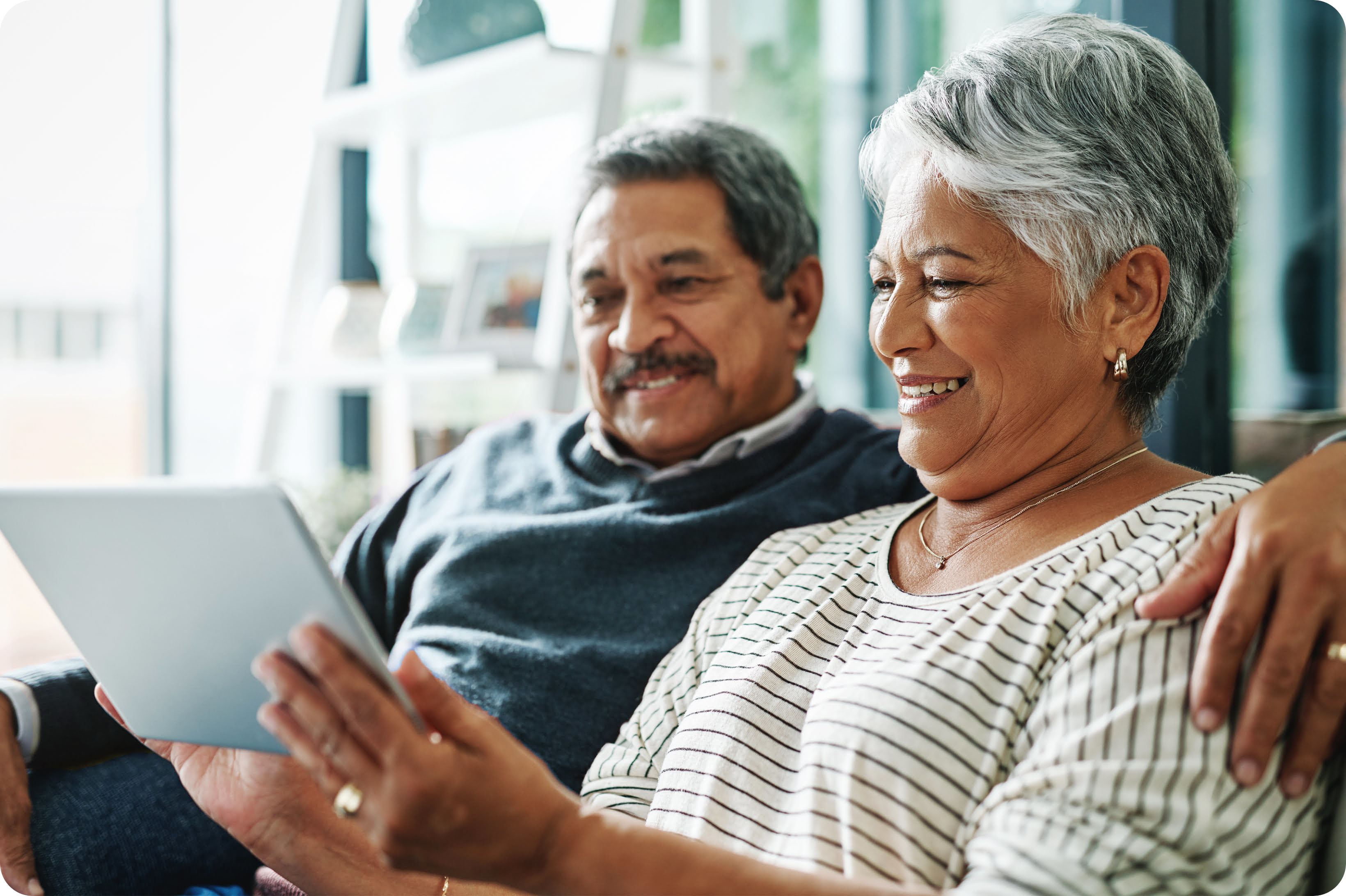 A couple on their couch looking at a tablet together