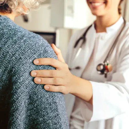 Closeup of a doctor’s hand on her patient’s upper arm